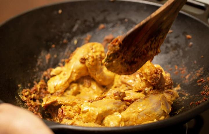 Adding marinated chicken to the pan